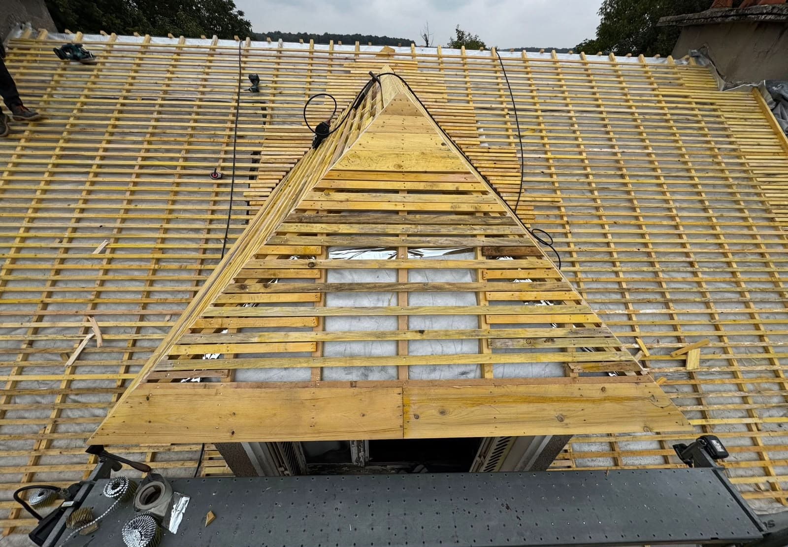 Toiture en bois en cours de rénovation avec des liteaux et une lucarne centrale.